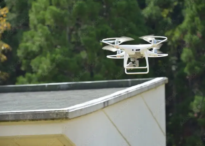建物屋上に浮かぶ白いドローンの写真