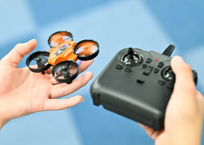 手に持った小型ドローンと操作コントローラー