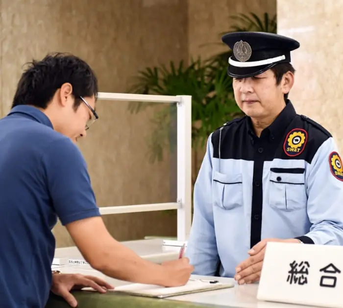 受付で案内をしている警備員